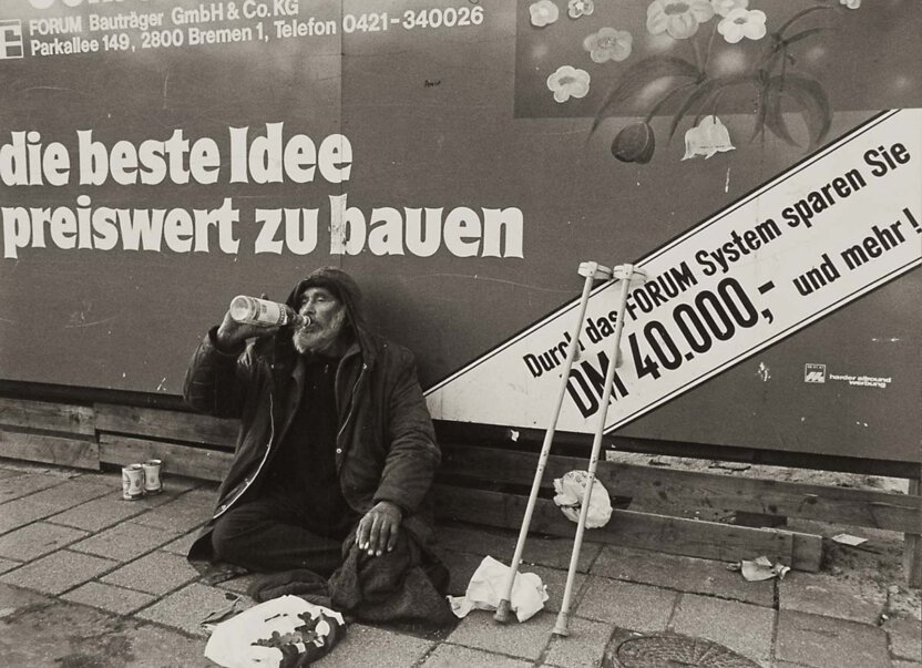 Werbeplakat "die beste Idee preiswert zu bauen" mit Obdachlose am trinken in Bremen