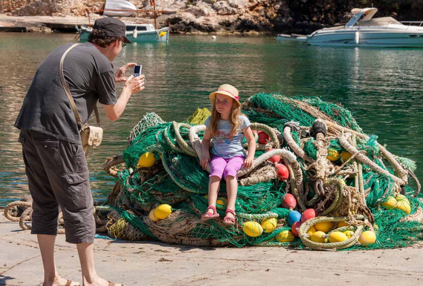 Mädchen sitz auf Fischernetze und wird fotografiert