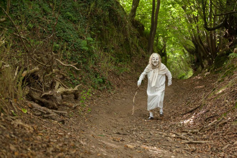 Alte Frau mit Stock im Wald in der Bretagne